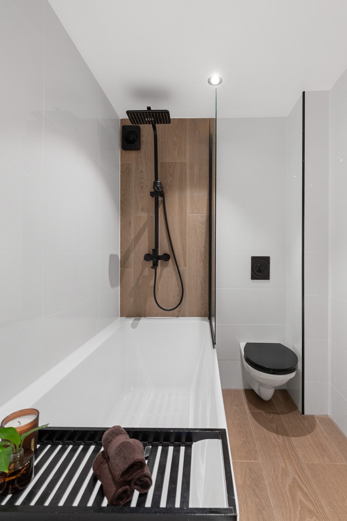 Badet er innredet med badekar med glassvegg, vegghengt servantinnredning, vegghengt toalett og speilskap med belysning. Galleribilde