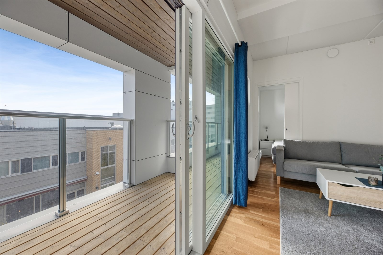 Den inntrukne balkongen på ca 8 kvm nås via skyvebalkongdøren fra stuen. Tregulv og tak over gir et lunt preg, og glassrekkverket holder utsikten åpen. Balkongen har plass til sittemøbler og er godt skjermet mot vær. Galleribilde