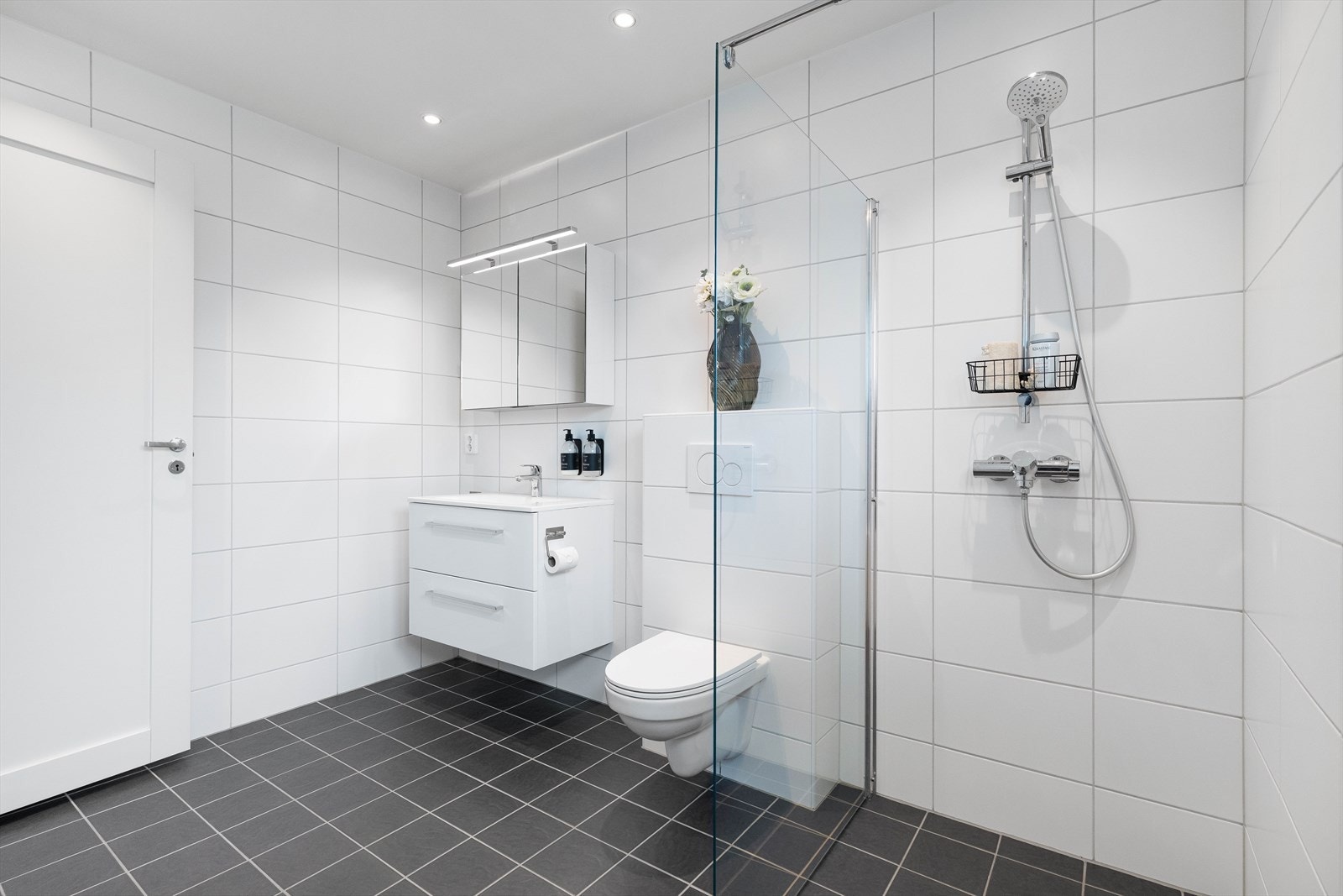 Badet i andre etasje er boligens største bad. Det er helfliset med lyse fliser på veggene og mørkere fliser på gulvet. Galleribilde
