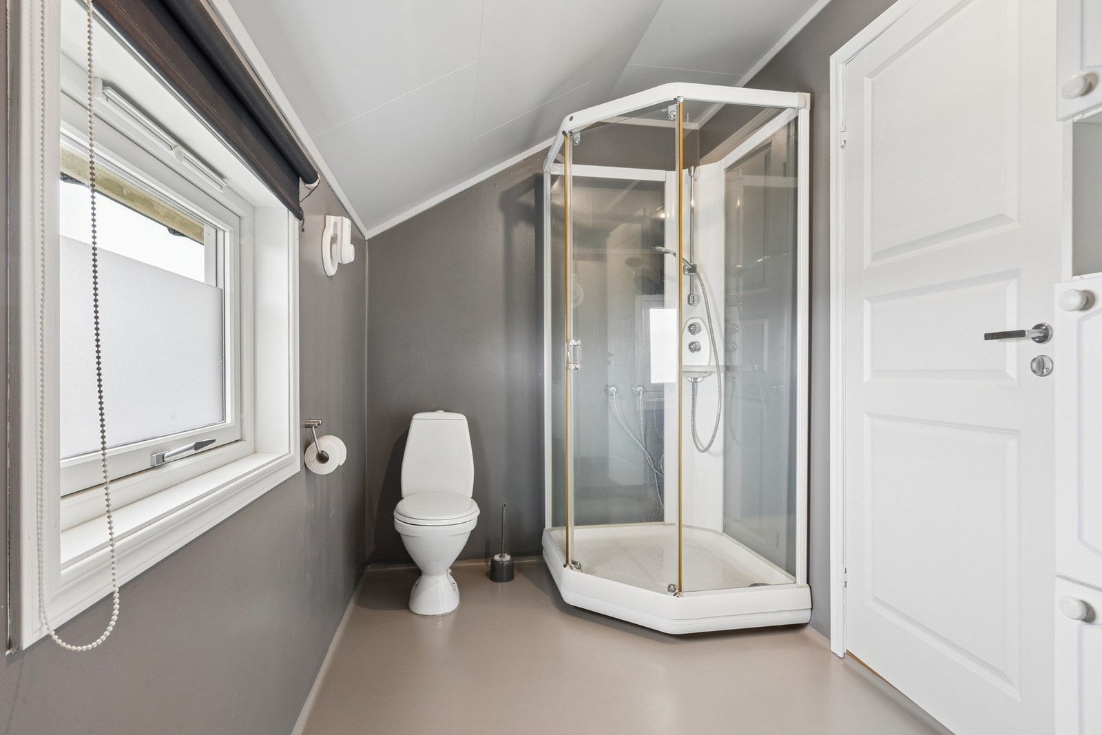 Badet er utstyrt med gulvmontert toalett og dusjkabinett. Galleribilde