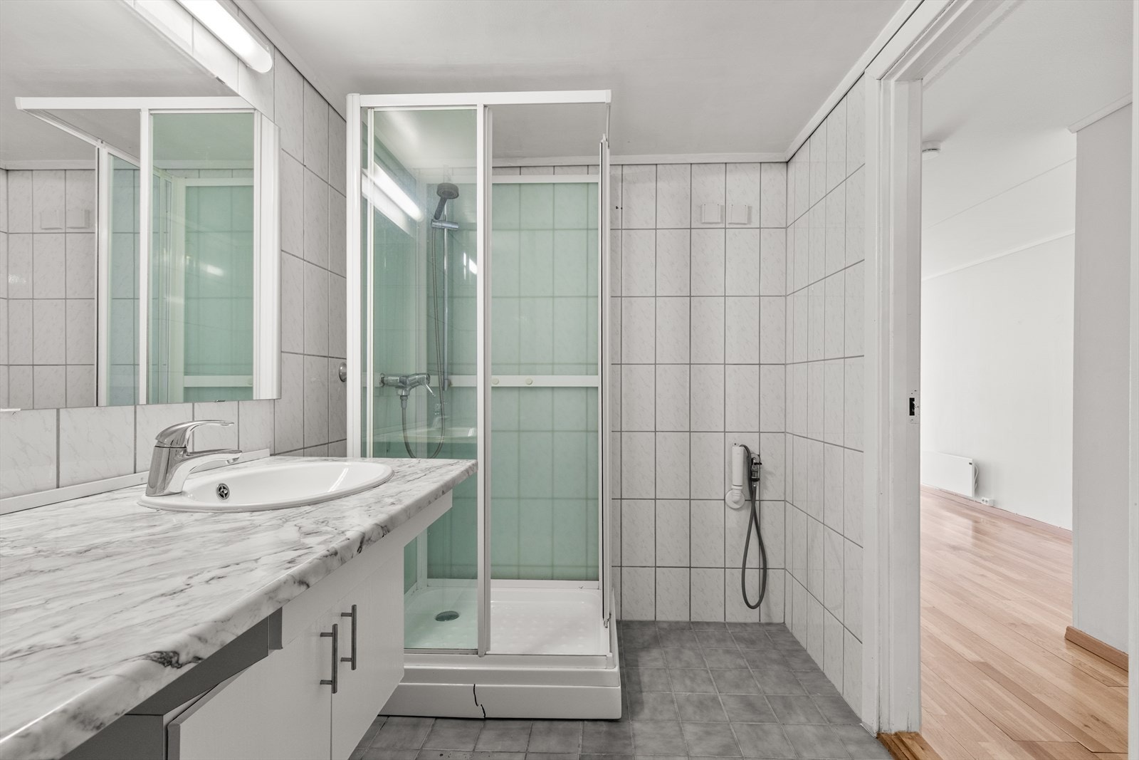 Flislagt bad fra byggeåret med varmekabler i gulv. Badet har en praktisk planløsning og fremstår som et funksjonelt våtrom med gode bruksmuligheter. Galleribilde