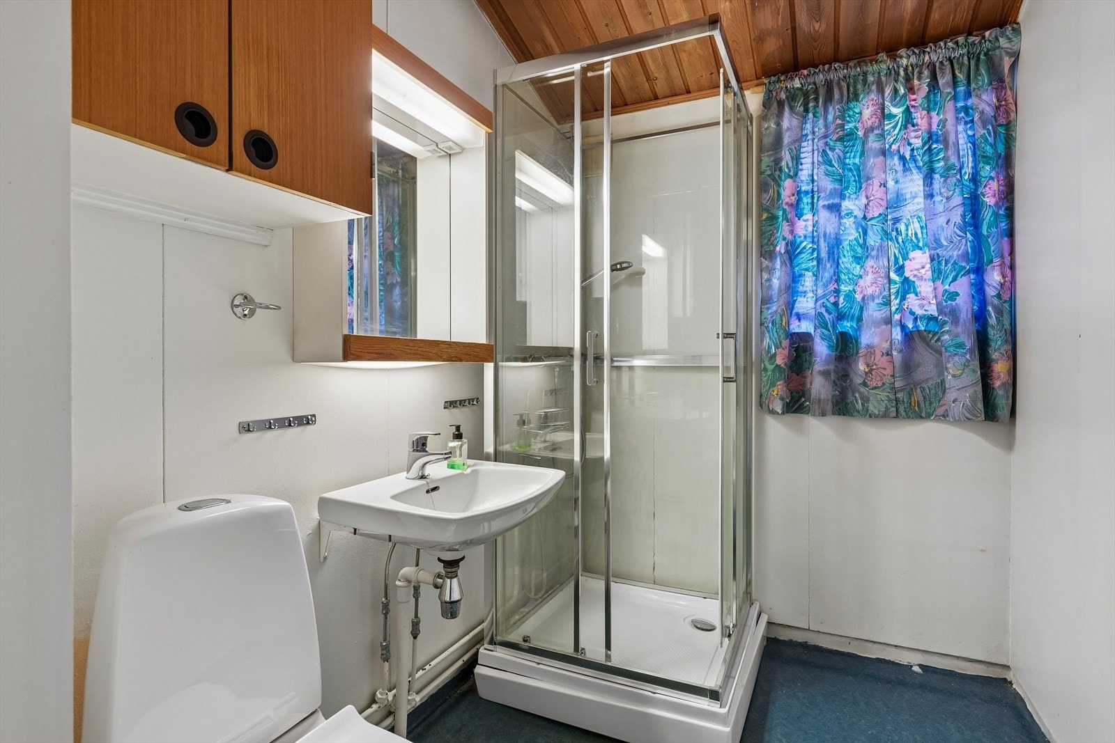 Badet i hovedetasjen er fra byggeåret og har belegg på gulv samt platekledde vegger. Rommet er innredet med servant, speil, overskap, dusjkabinett og toalett. Galleribilde
