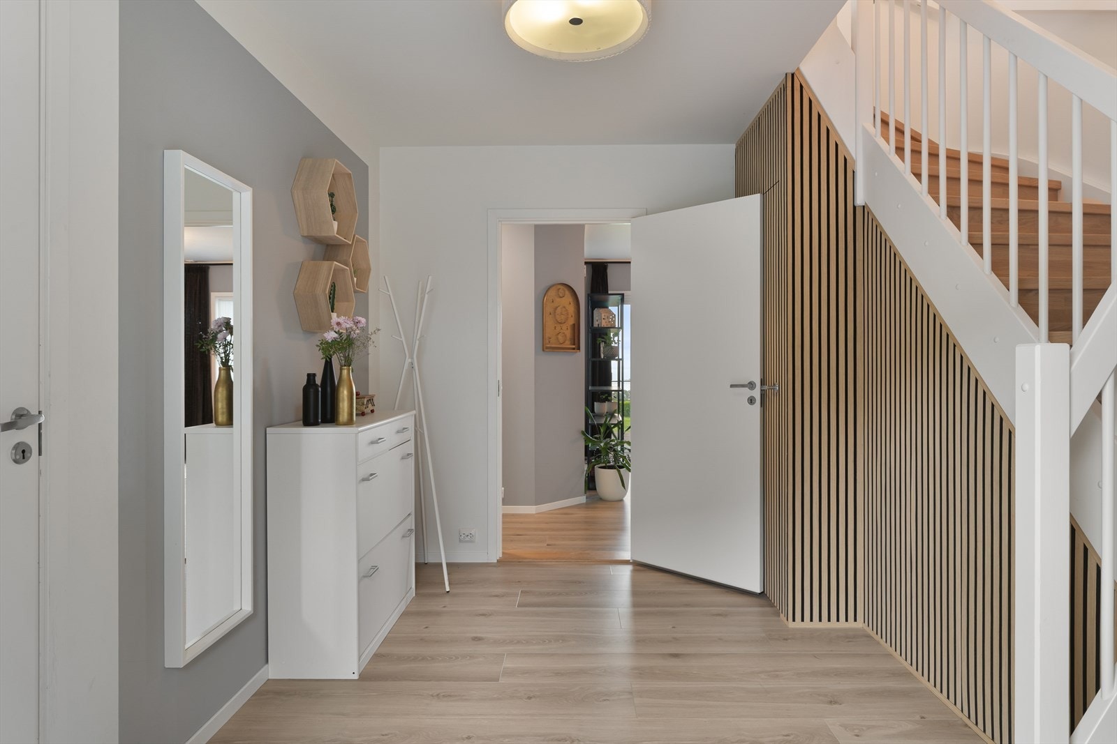 Romslig entré med gode muligheter for garderobeløsninger. Praktisk og smart oppbevaring er etablert bak en stilren spilevegg under trappen. Galleribilde