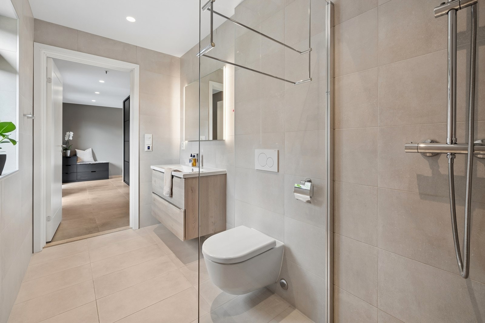 Badet i 1. etasje er utstyrt med dusj med faste glassfelt og dør i herdet glass, servant med tilhørende innredning med glatte fronter, speil og veggmontert toalett med innebygget sisterne. Galleribilde