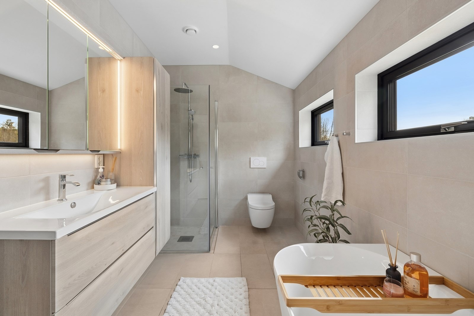 Badet i 2. etasje er romslig og funksjonelt, med både dusjnisje, badekar, servant med innredning bestående av benkeskap og høyskap, speil samt veggmontert toalett med innebygget sisterne. Galleribilde