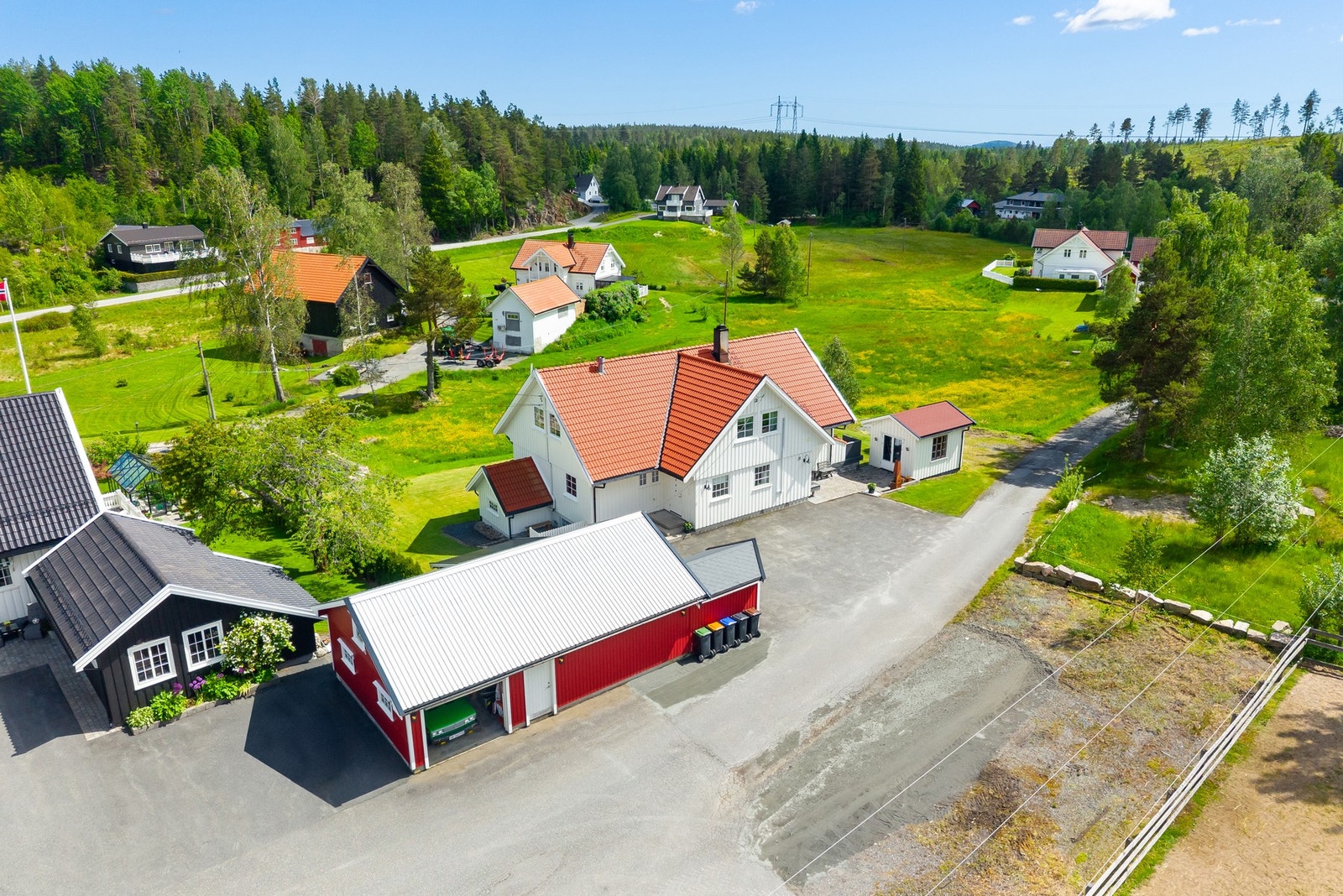 Oversiktsbilde av eiendommen og området. Boligen har pent opparbeidet plenareal, utestue, garasje og asfaltert innkjørsel. Galleribilde