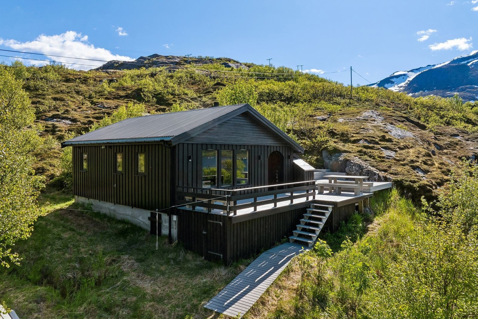 Hytten ligger fint til ved veis ende - på et høydedrag med fantastisk utsikt utover havet og fjellene omkring.