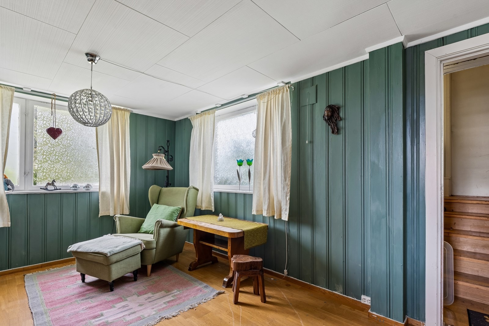 Veggene i rommet er kledd med panel, og vinduene slipper inn dagslys. Galleribilde