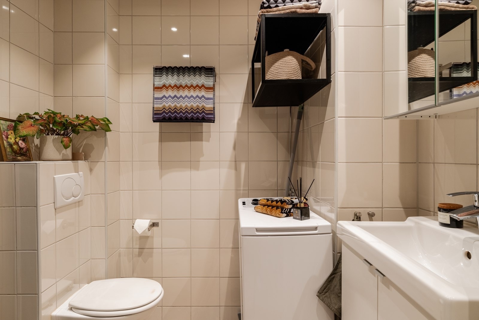 Flislagt bad med elektrisk gulvvarme og opplegg for vaskemaskin. Innredningen er fra 2018. Galleribilde