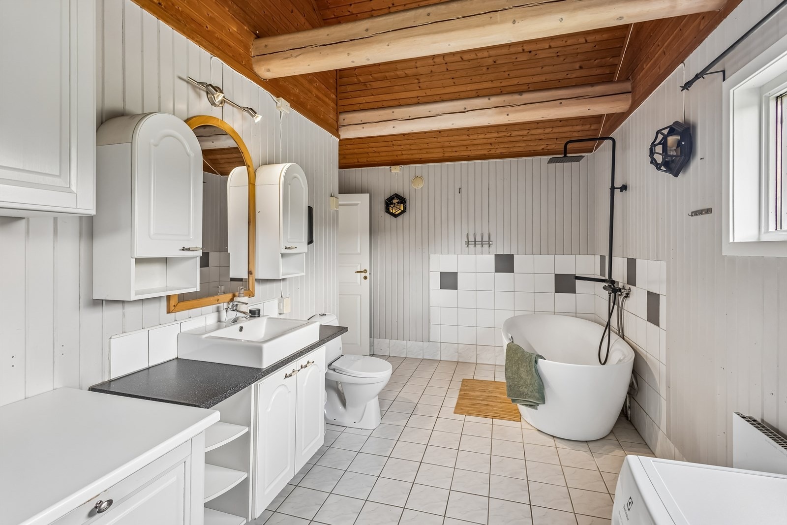 Badet i første etasje er kombinert bad/vaskerom, innredet med badekar, toalett, dusj og opplegg for vaskemaskin. Galleribilde