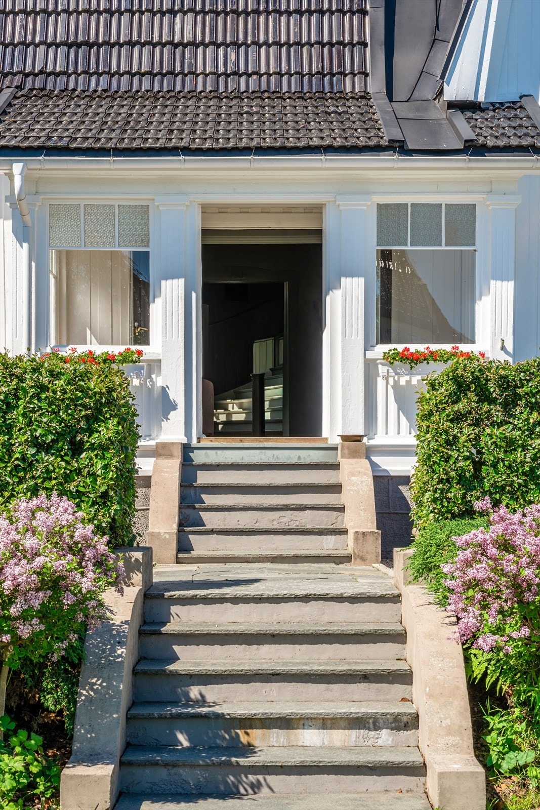 Tidstypiske trapper fra innglasset veranda til terrasse og videre ned til det vakre hageområdet Galleribilde