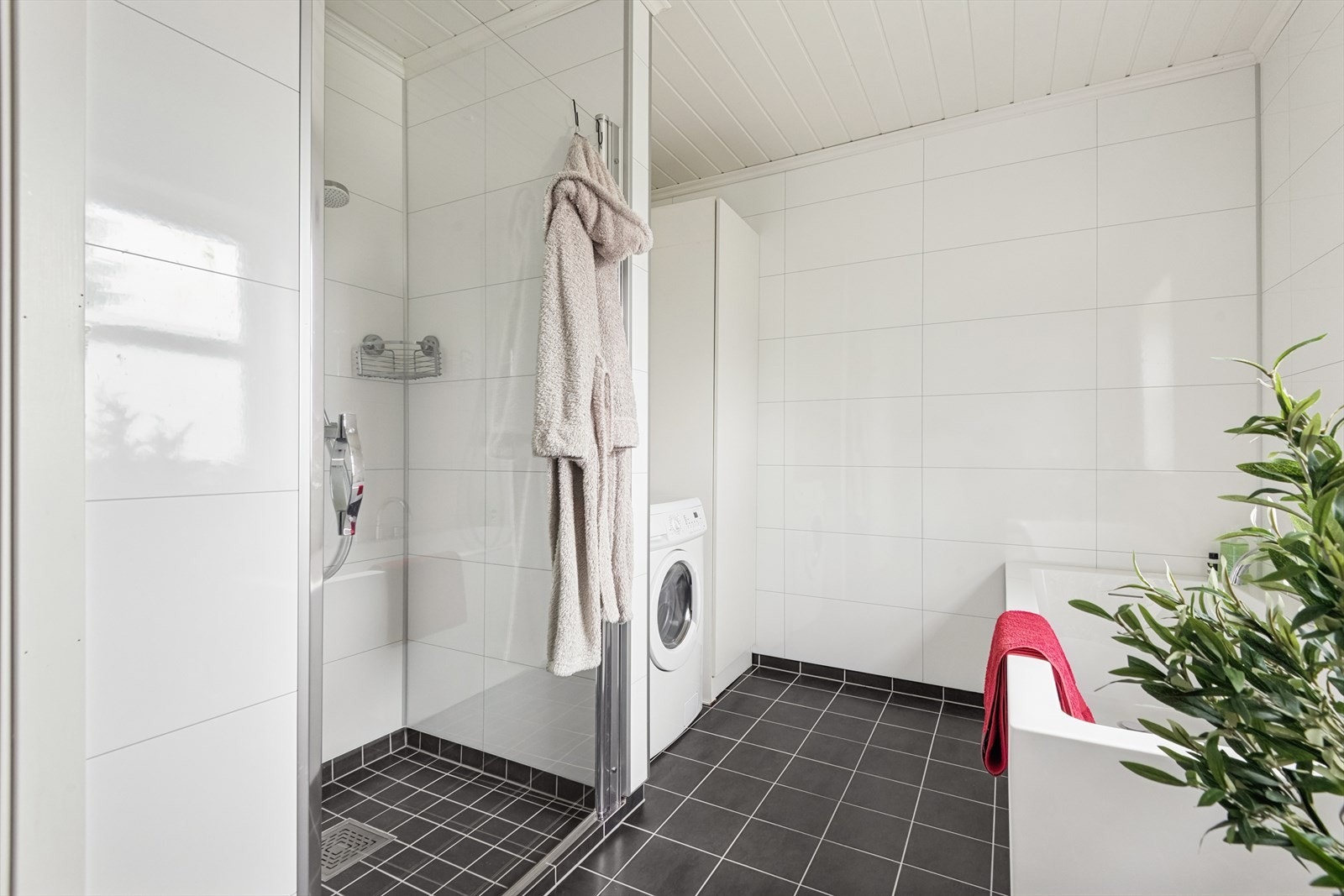 Badet har vegghengt toalett, dusj med glassdør, badekar og opplegg for vaskemaskin. Galleribilde