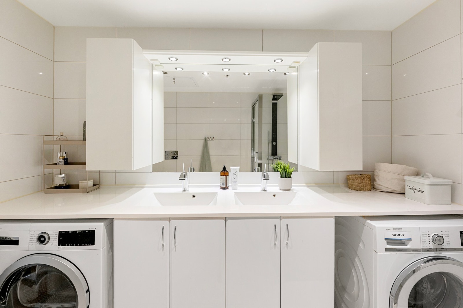 Bad 2 (en suite ved hovedsoverommet) har helflisede vegger og gulv. På badet er det hvit, glatt innredning med to helstøpte servanter i benkeplaten, speil og godt med skapplass. I tillegg er det dusj med glassdører, vegghengt wc og opplegg for vaskemaski Galleribilde