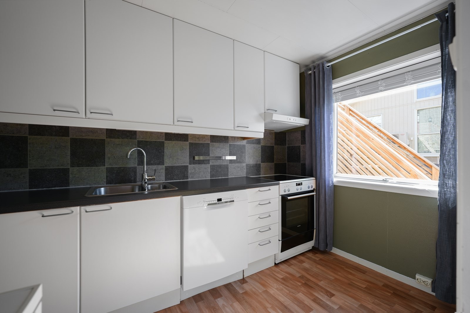 Kjøkkenet har innredning med glatte fronter. Benkeplaten er av laminat. Det er oppvaskmaskin og komfyr. Det er kjøkkenventilator med avtrekk ut. Galleribilde