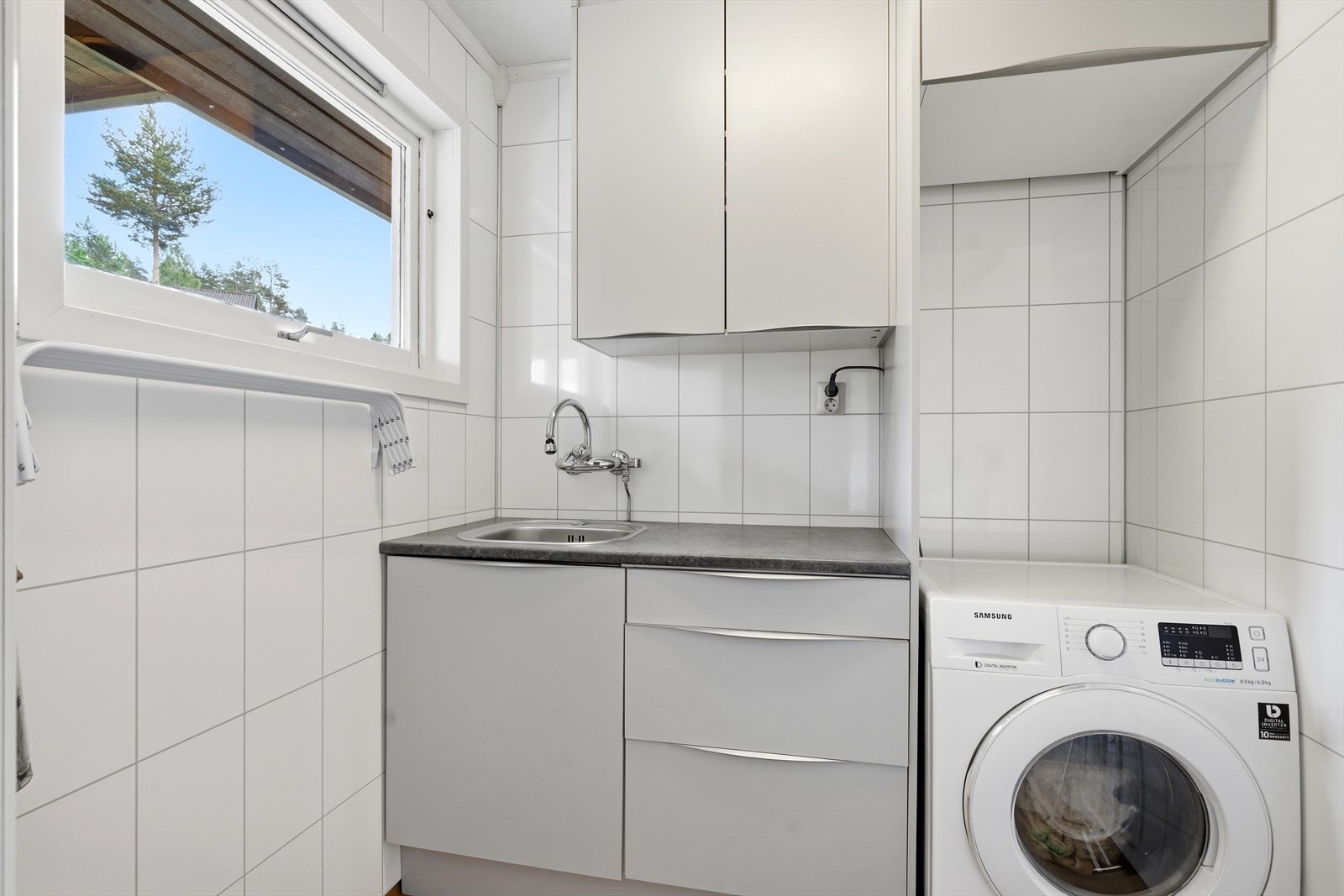 Praktisk vaskerom med innredning, servant og opplegg for vaskemaskin. Galleribilde