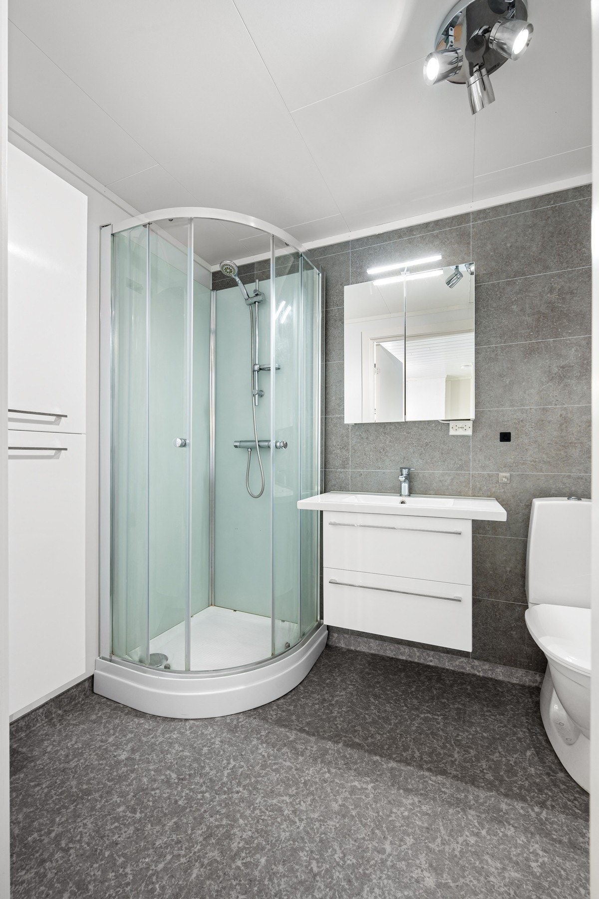 Badet har varmekabler i gulvet og inneholder vegghengt servantinnredning, dusjkabinett, toalett og røropplegg for vaskemaskin Galleribilde