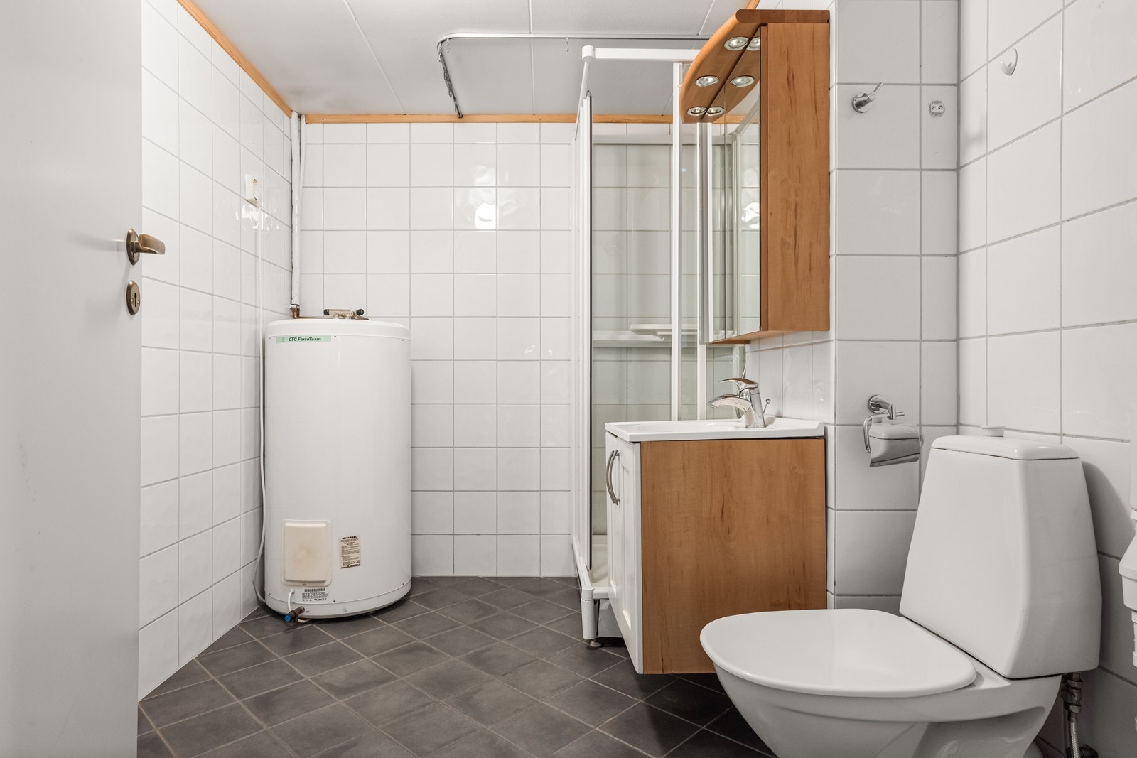 Flislagt bad med elektrisk gulvvarme, dusjkabinett og opplegg for vaskemaskin. Galleribilde