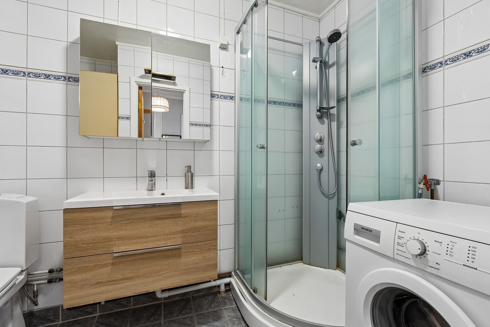Badet er flislagt, og er innredet med et praktisk dusjkabinett. Galleribilde
