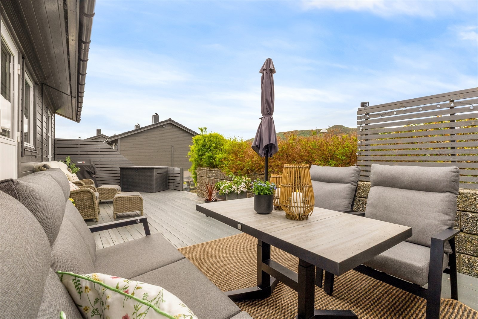 Fra terrassen har man utsyn over hagen og nærområdet, og det er plass til både spisegruppe, lounge-møbler og grill Galleribilde
