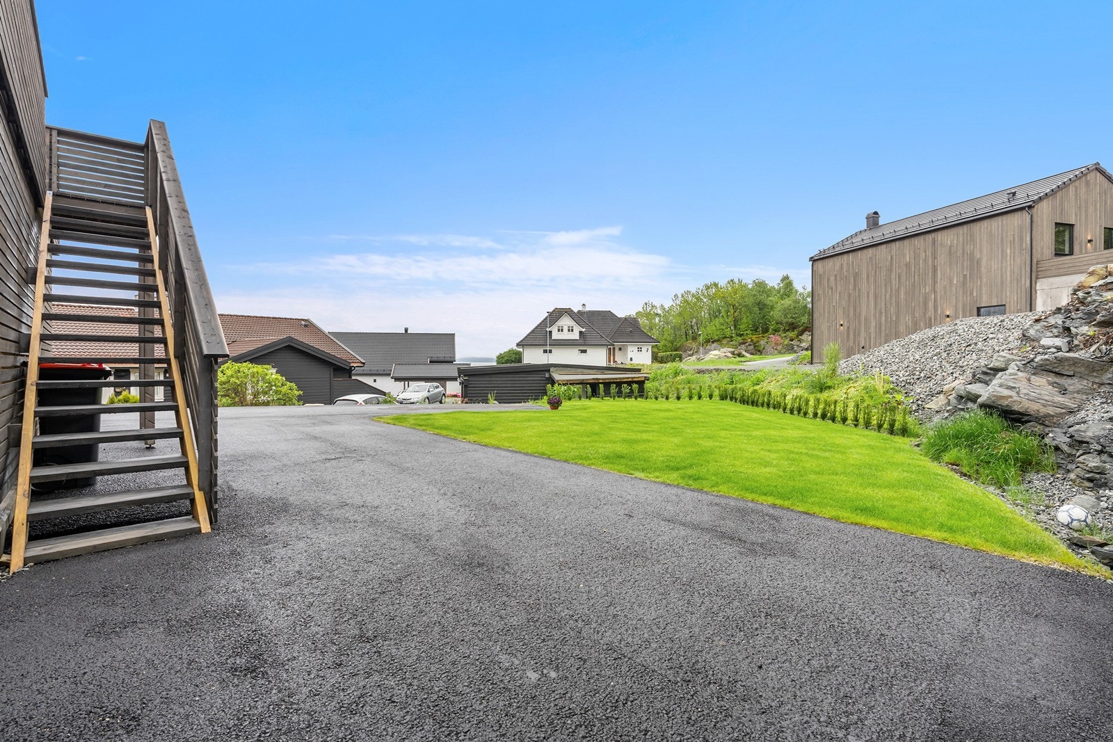 Fra balkongen er det trapp ned til asfaltert tun. Tomten er pent opparbeidet. Galleribilde