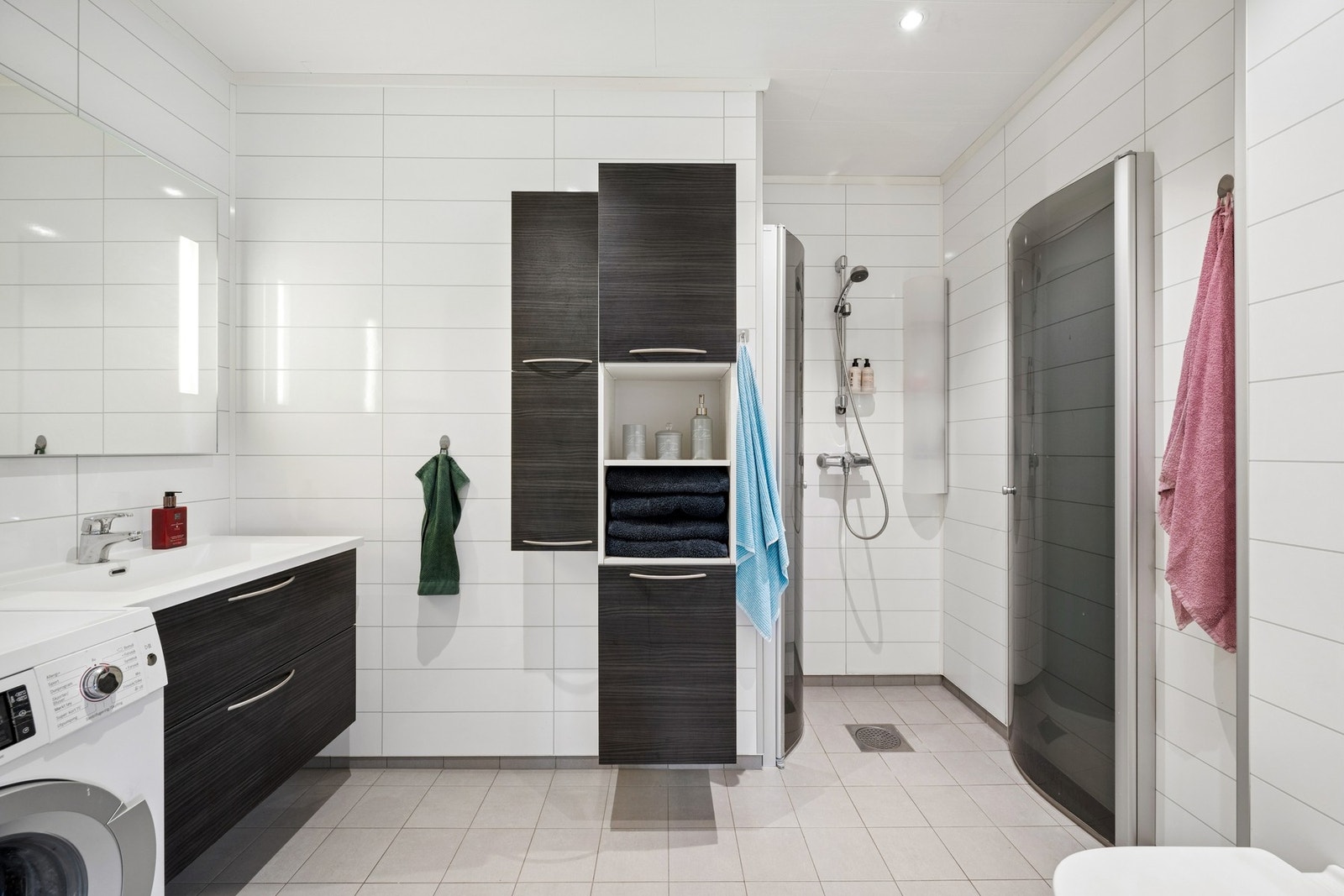 Badet er utstyrt med dusjkabinett, vegghengt toalett og servant med underskap. Galleribilde