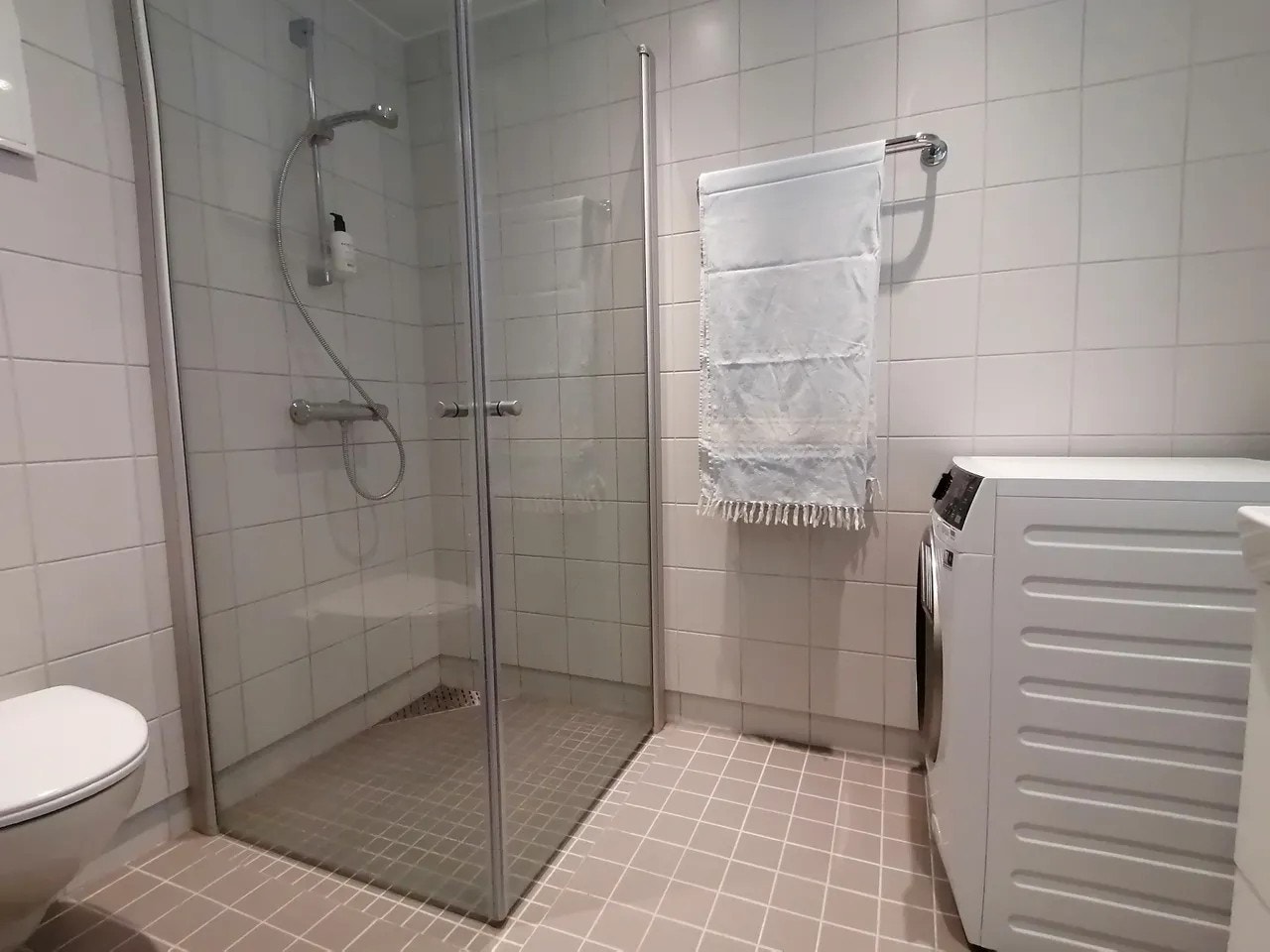 Pent flislagt bad med vegghengt toalett, hjørnedusj og servant m/innredning. Galleribilde