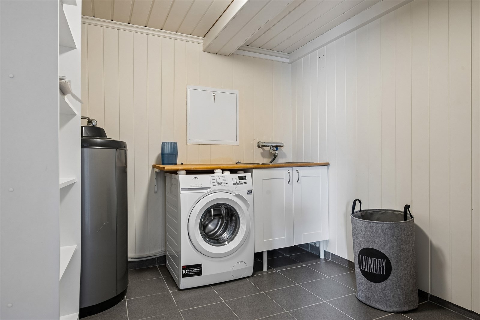 Separat vaskerom med flislagt gulv med elektriske varmekabler, utslagskum og opplegg for vaskemaskin. Galleribilde