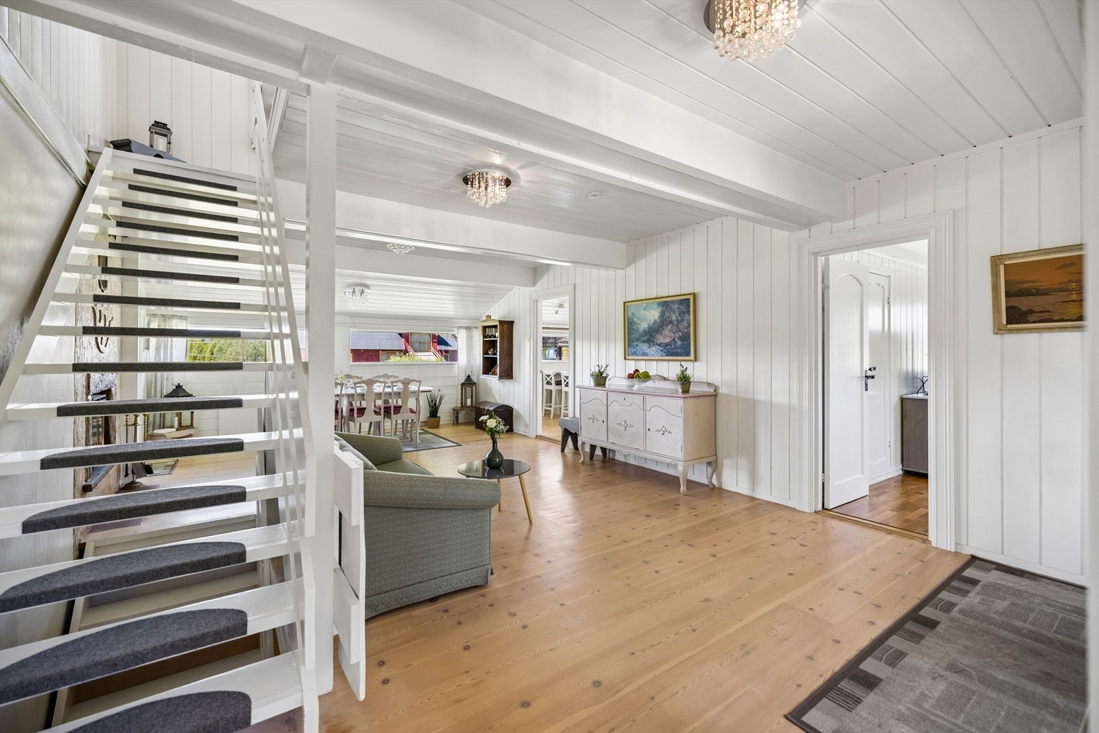 Boligen har flere stuer og sosiale soner. Her med heltre på gulv og malt panel i taket. Galleribilde