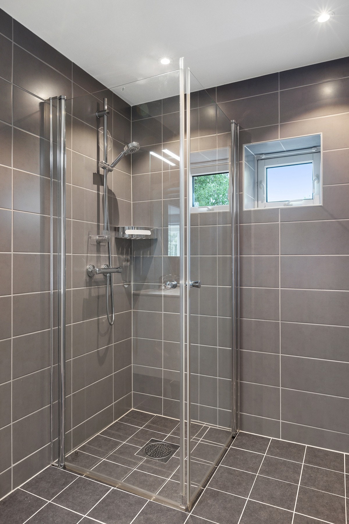 Badet har flislagte overflater og innfelte downlights i himlingen Galleribilde