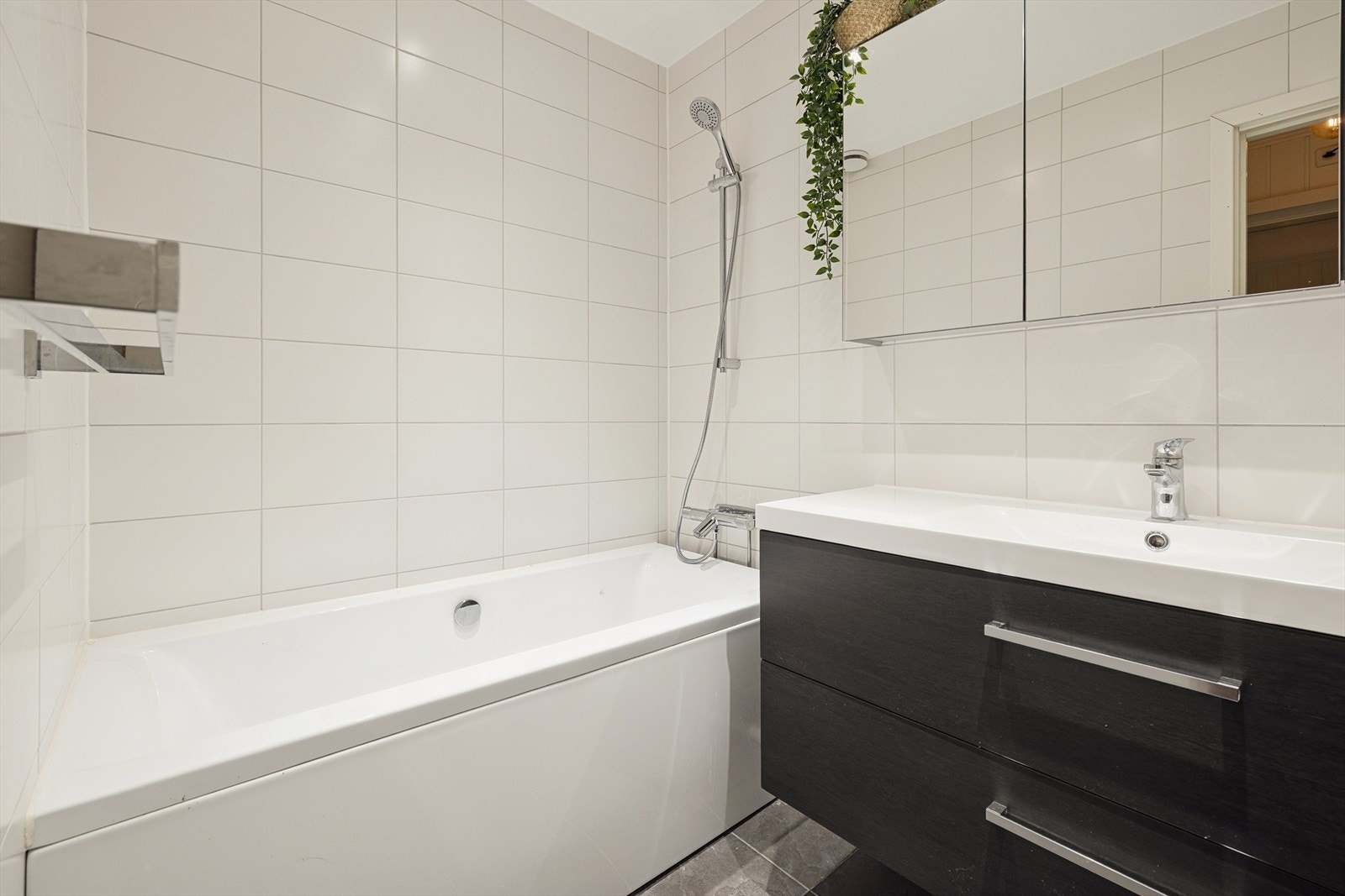 Lyst og moderne bad med flislagte overflater, stilren servantinnredning med god oppbevaringsplass og speilskap over servant. Galleribilde