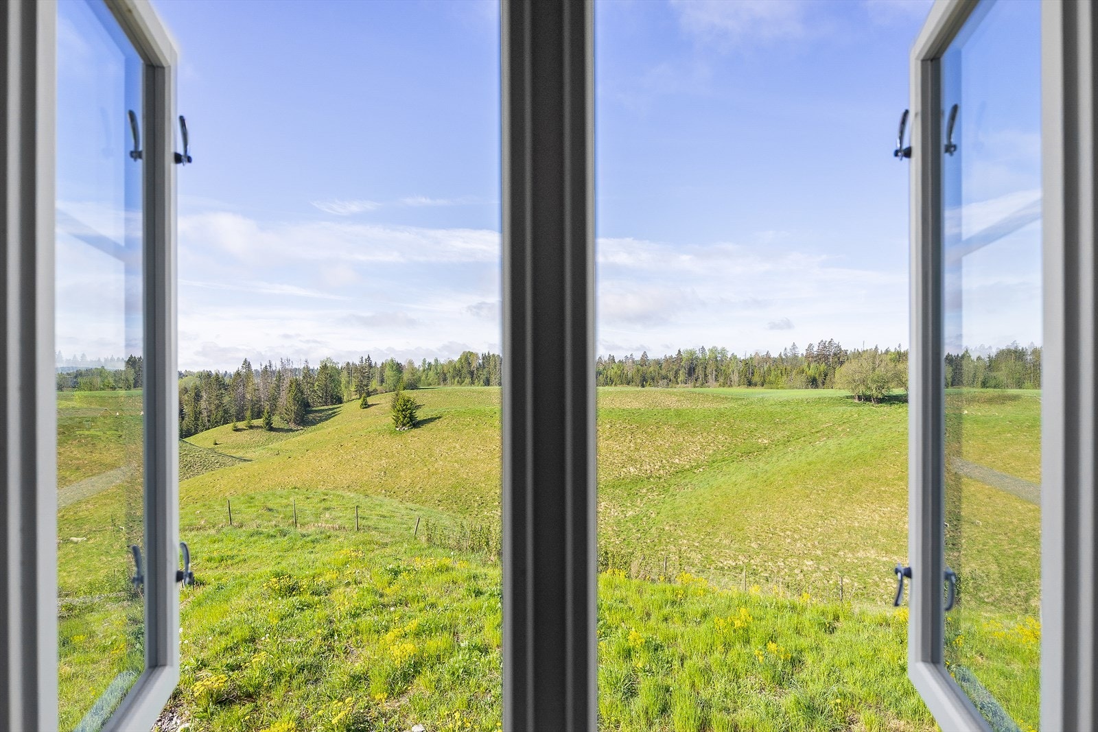 Fra vinduene har man fri utsikt over jorder og skog. Galleribilde