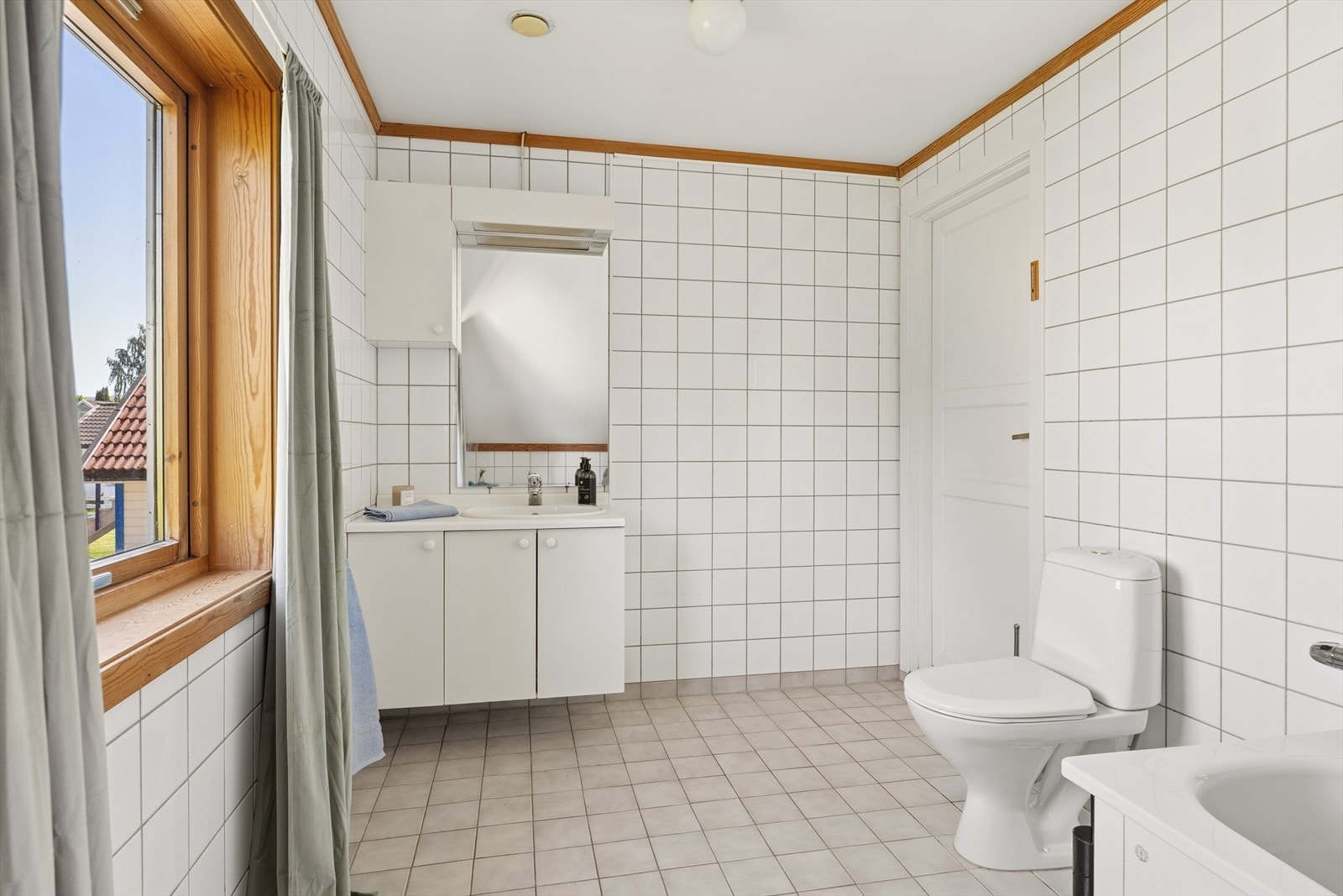 Romslig bad fra byggeår med flislagte overflater. På badet er det montert et badekar, et toalett og en baderomsinnredning. Våtrommet må oppgraderes for å tåle normal bruk etter dagens krav. Galleribilde