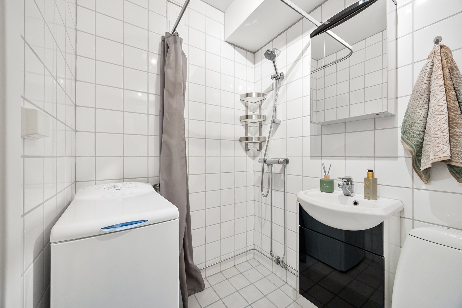 Badet inneholder dusjnisje, vegghengt servant, toalett og opplegg for vaskemaskin Galleribilde