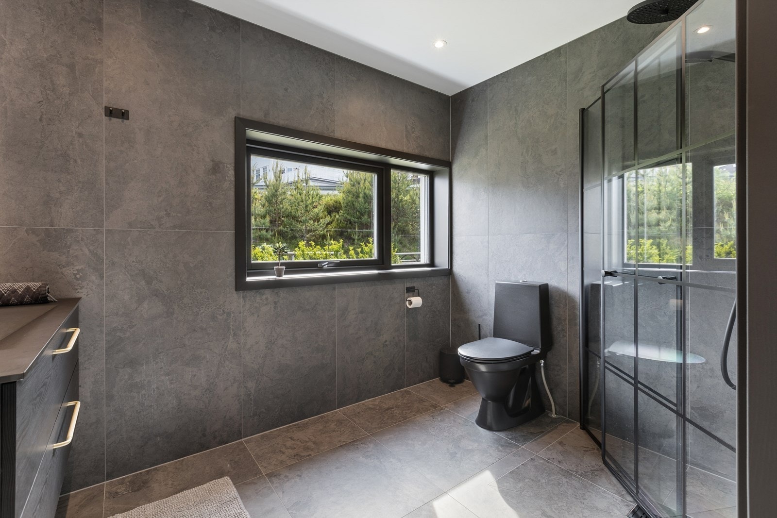 Stilren servantinnredning, speil med belysning og elegante sorte detaljer gir badet et eksklusivt preg. Galleribilde