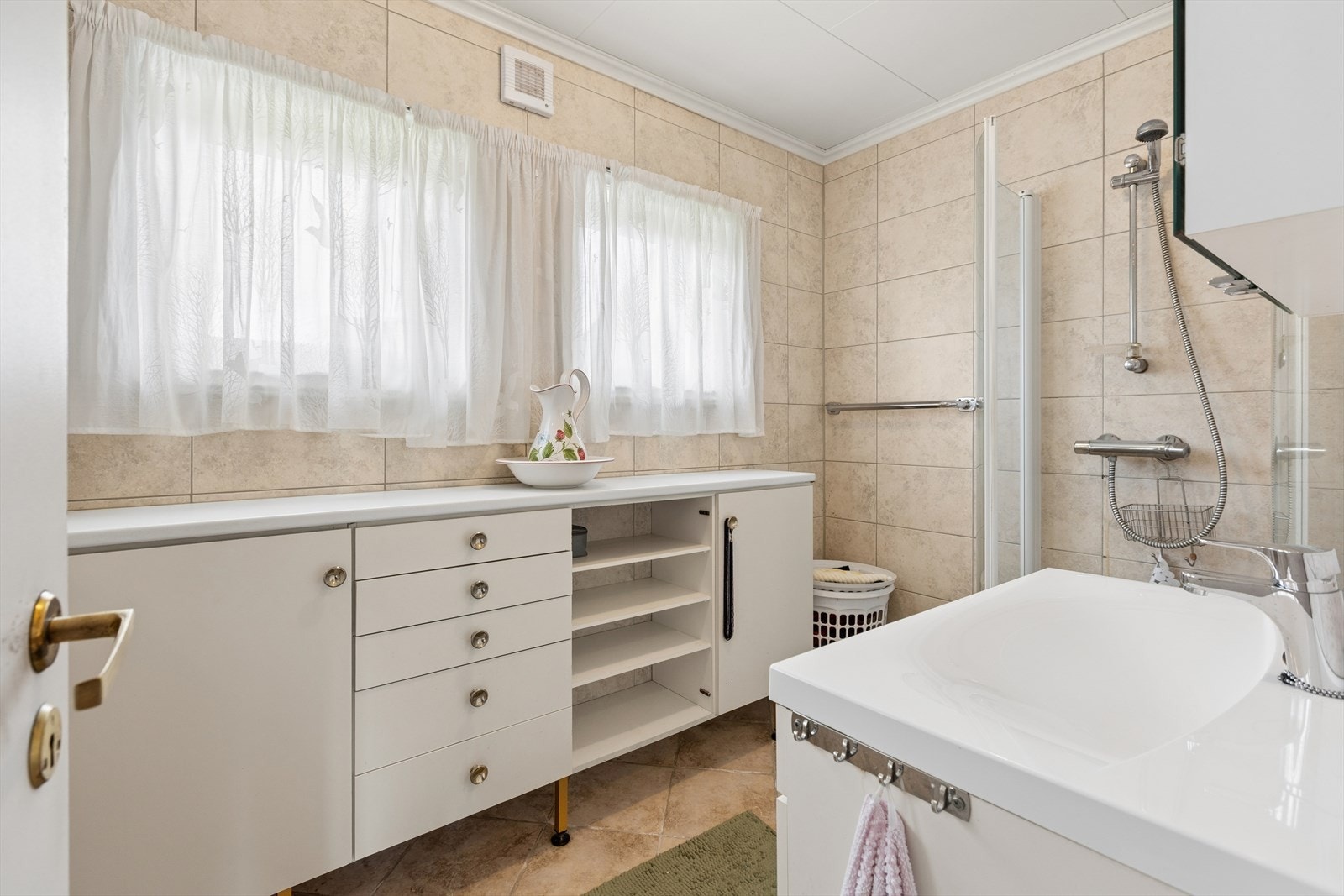 Baderommet ligger i 2. etasje og er utstyrt med servant med underskap, dusjhjørne med glassdører samt en bred baderomsinnredning med god lagringsplass. Badet har behov for modernisering. Galleribilde