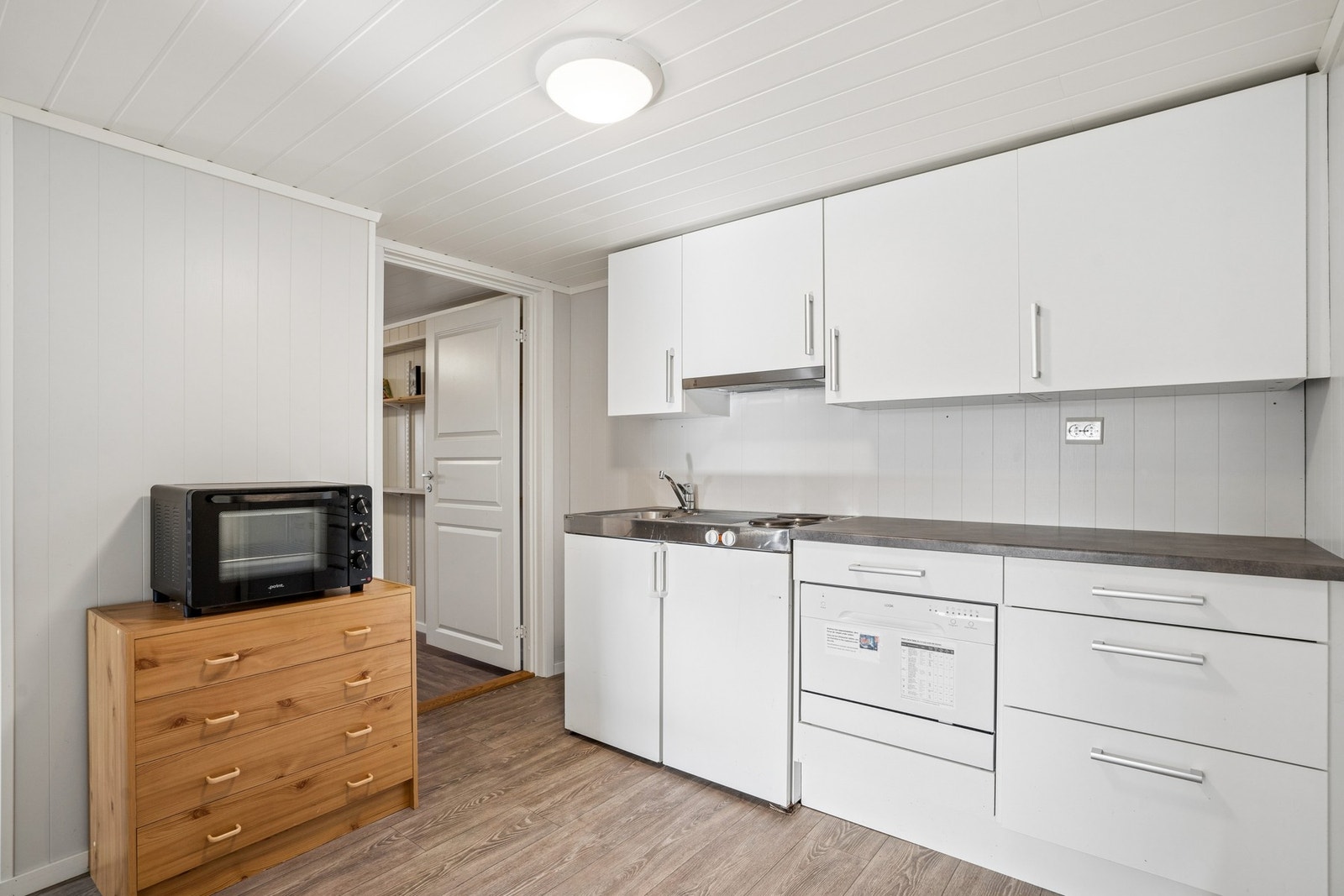 Kjøkkeninnredning med laminat benkeplate, hybelkomfyr med kjøleskap og liten oppvaskmaskin. Galleribilde