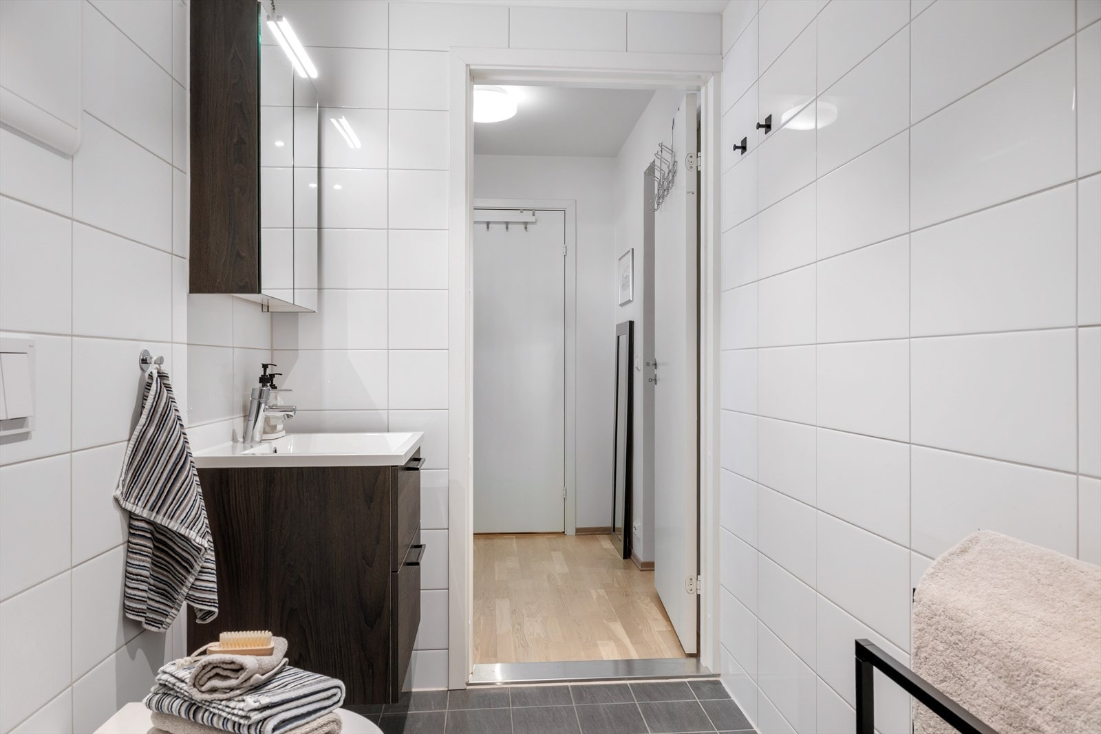 Moderne og romslig bad med vegghengt servant, speilskap, dusjnisje og opplegg til vaskemskin/tørketrommel. Galleribilde
