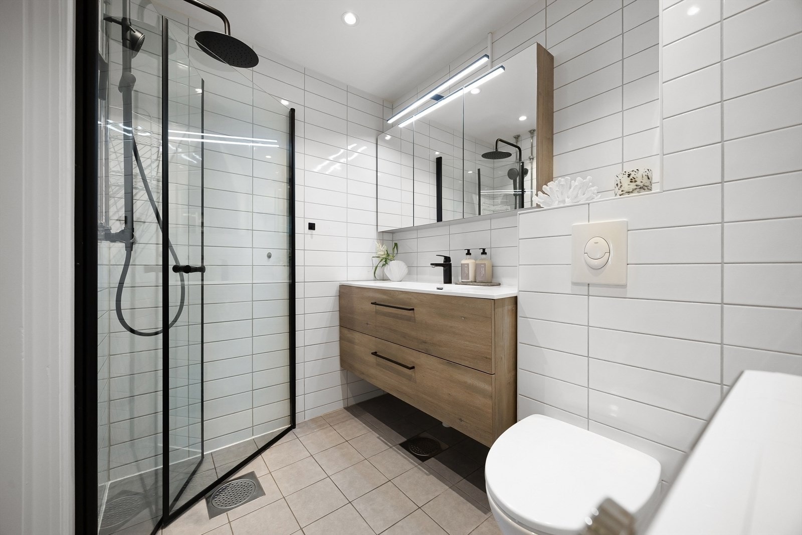 Romslig bad med flislagte vegger og gulv, samt nyinstallert termostat og nymonterte LED-downlights fra 2024. Galleribilde