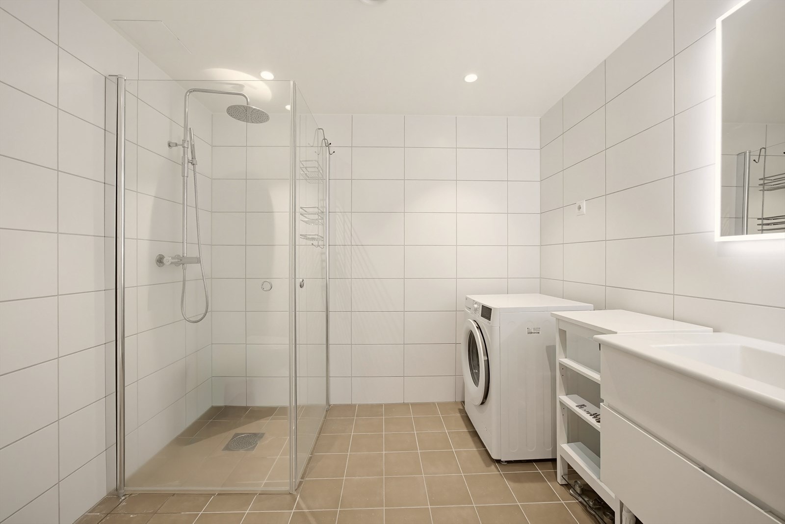 Badet har en moderne utførelse med grå fliser på gulv og hvite fliser på veggene, som gir et stilrent og tidløst uttrykk. Galleribilde