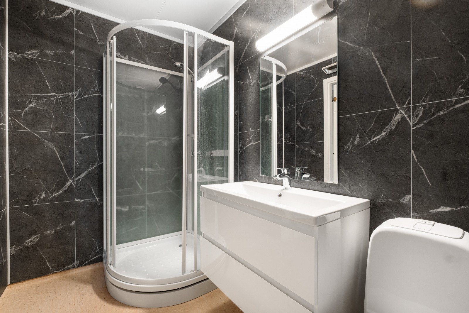 Badet er utstyrt med dusjkabinett, servant nedfelt i innredning, toalett og opplegg for vaskemaskin. Galleribilde