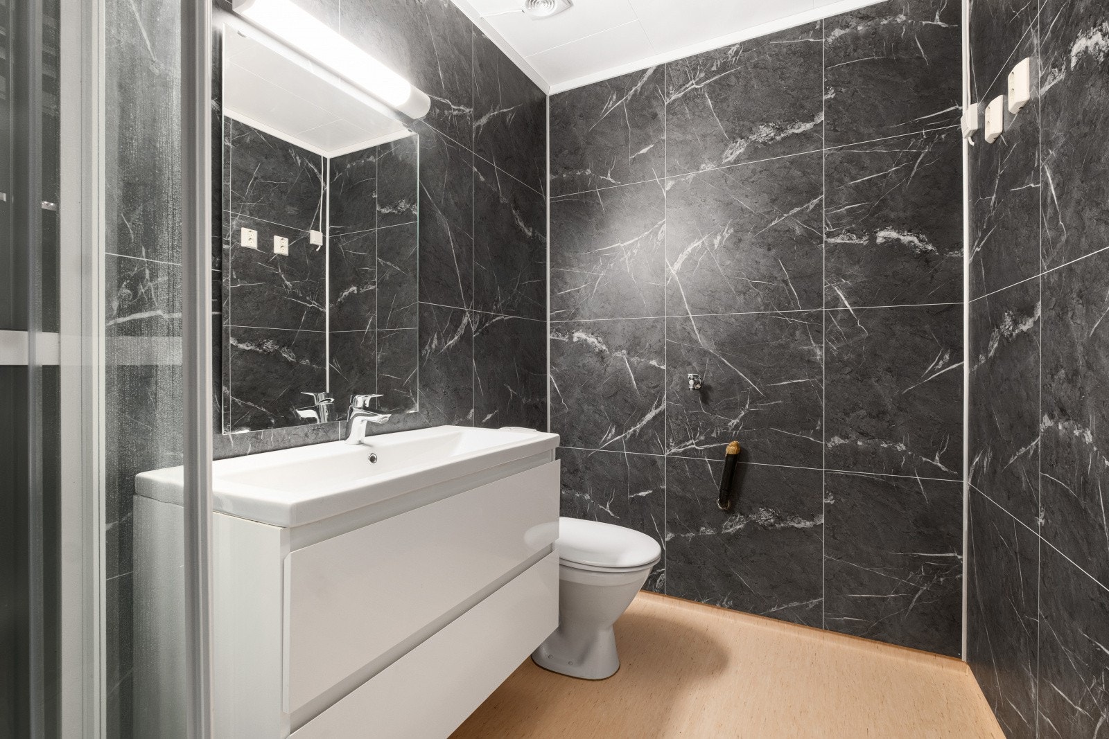 Badet har våtromsplater på vegger og belegg på gulvet. Galleribilde