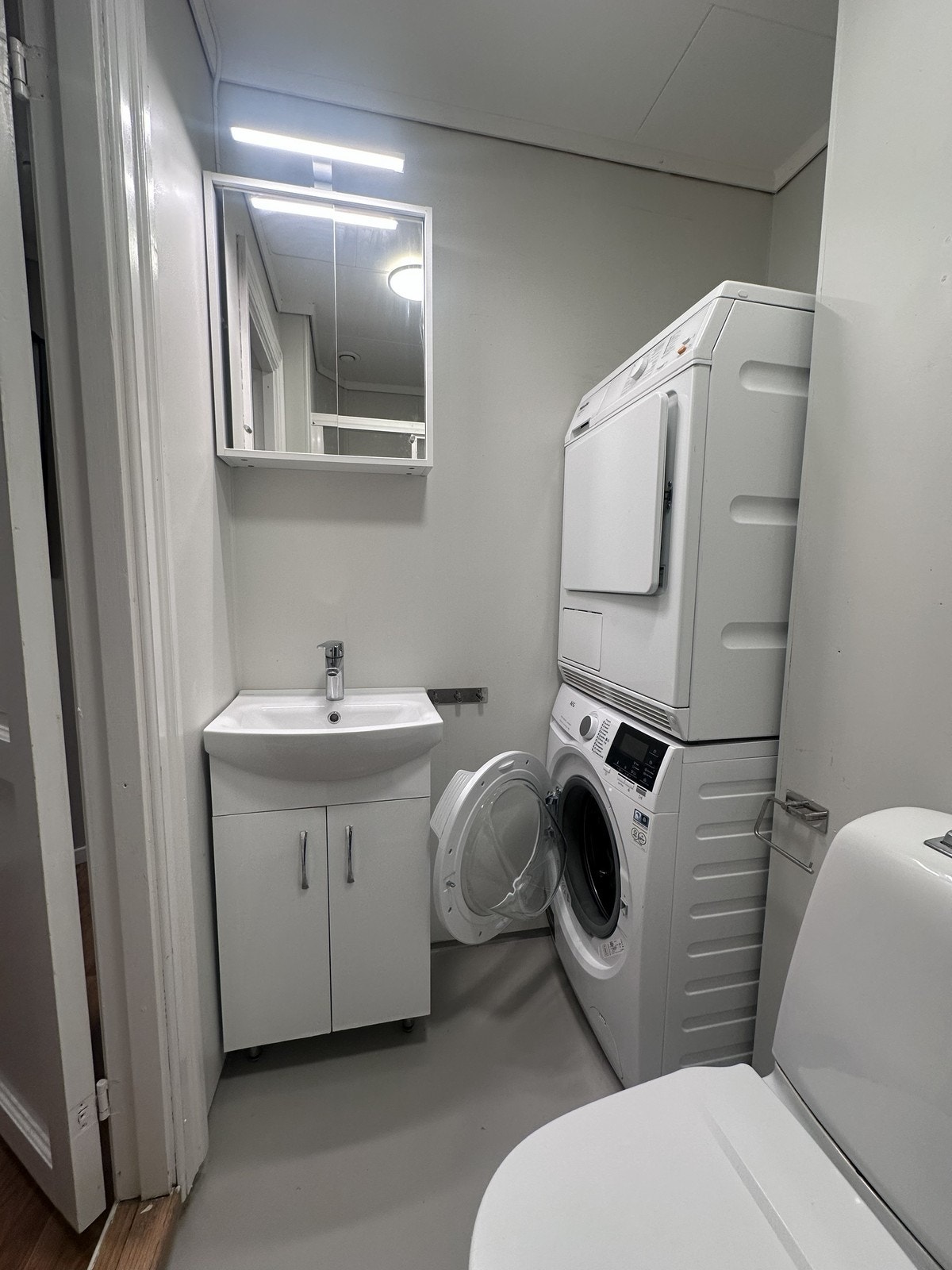 Badet er innredet med toalett, servant, dusj og vaskemaskin Galleribilde