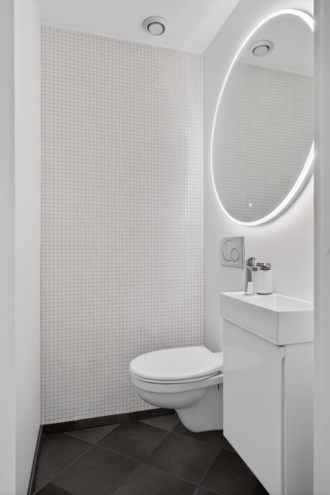 Praktisk toalettrom med vegghengt toalett og innredning med nedfelt servant. Galleribilde