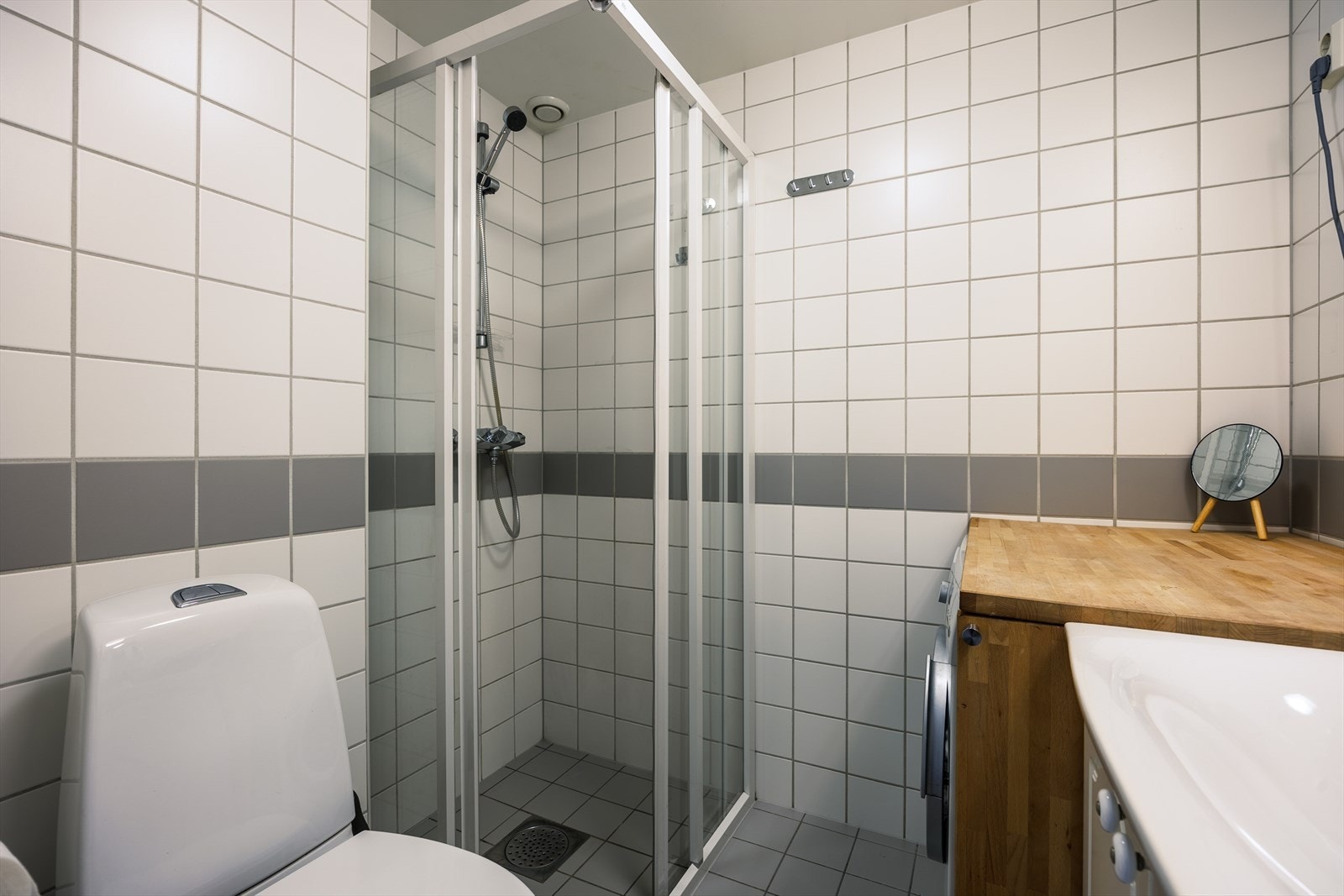 Badet i hybelen er også fra 2005. Baderommet har lysegrå fliser på gulv med gulvvarme, hvite fliser på vegger og avtrekksventil i himling. Galleribilde