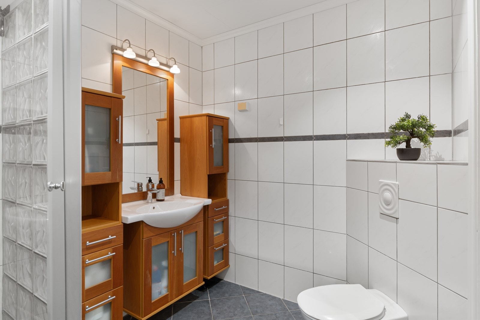 Flislagt bad med gulvvarme, veggmontert toalett og innredning med nedfelt servant. Galleribilde