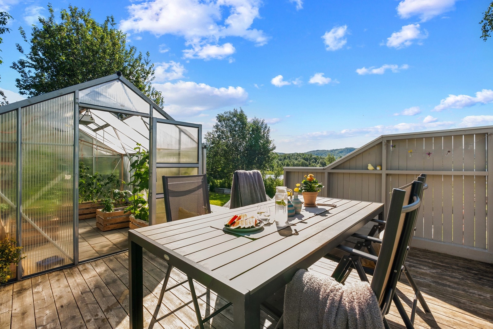 Pent opparbeidet terrasse-sone omringer drivhuset Galleribilde