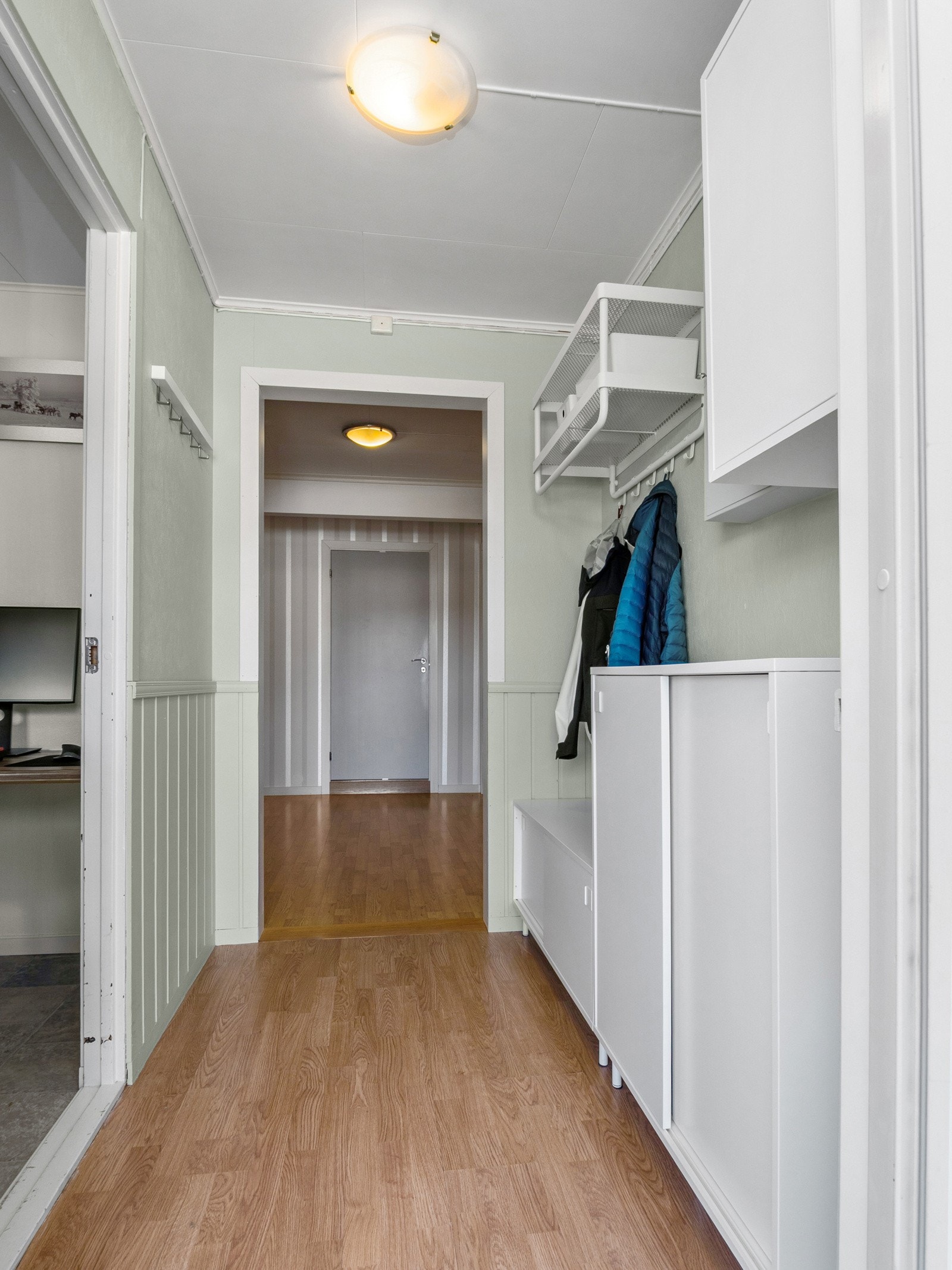 Man kommer inn i et vindfang med plass til både klær og sko, og her er det også inngang til et soverom Galleribilde