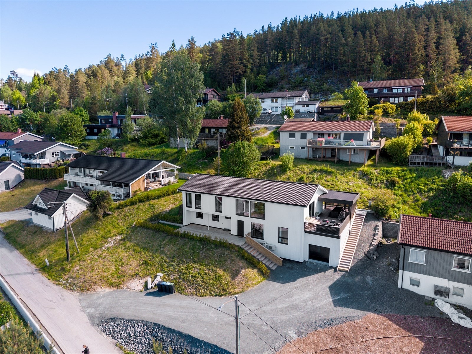 Tomten ligger i skrånende terreng og er pent opparbeidet med plen, beplantning, terrasser og trapper i terrenget. Galleribilde