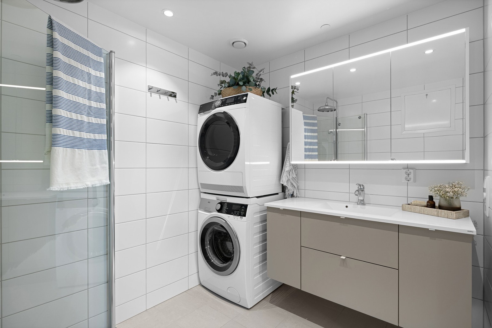 Badet er utstyrt med vegghengt toalett, dusjhjørne med innfellbare glassdører og opplegg for vaskemaskin og tørketrommel. Galleribilde