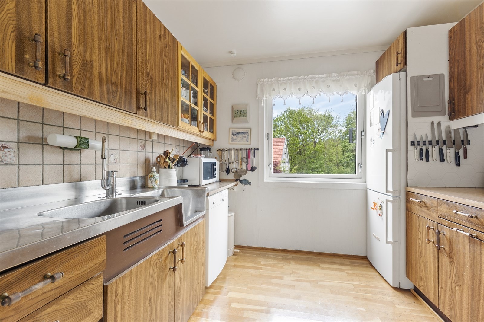 Kjøkkenet har eldre innredning med glatte fronter, laminat benkeplate og heltrukket benkebeslag i rustfritt stål. Galleribilde